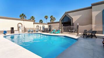 Una piscina al aire libre, sombrillas, sillones reclinables de piscina