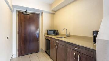 A compact kitchen with a microwave, sink, and coffee maker.