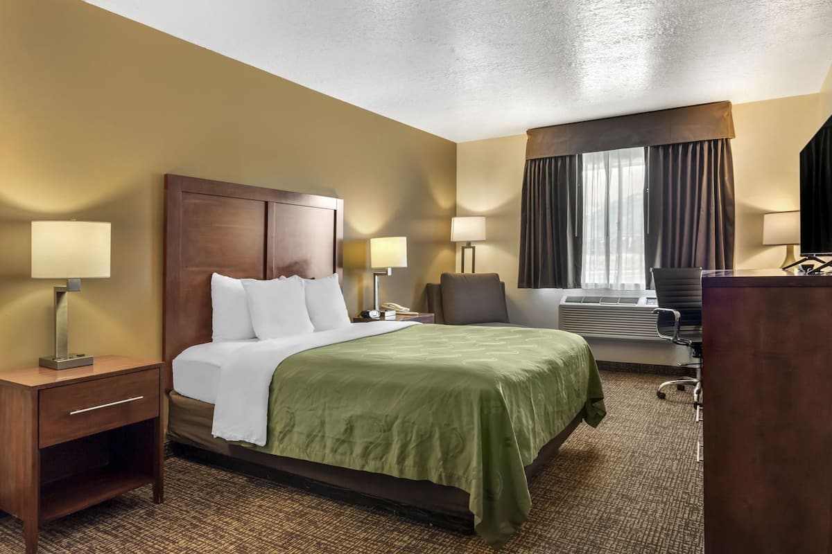 Ein Hotelzimmer mit Bett, Nachttischen, Lampen, Schreibtisch und Stuhl.