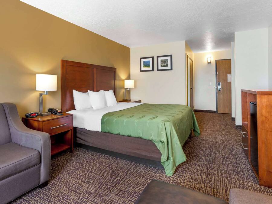 Una habitación de hotel con cama, escritorio con lámpara, silla y televisor.