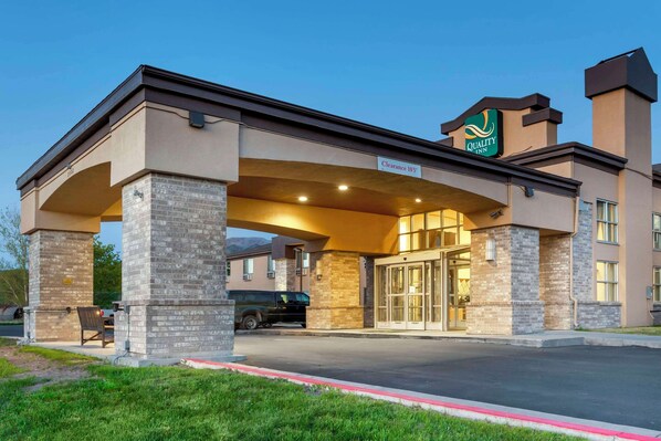 A hotel entrance with a covered waiting area, a clear sign indicating "Clearance 105", and a "Quality Inn" sign above the entrance.