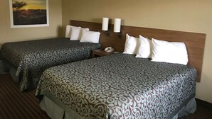 A hotel room with two beds, a nightstand, a phone, and a painting of a sunset on the wall. - Days Inn By Wyndham Lexington/Columbia (Lexington)