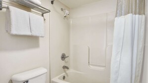 A bathroom with a toilet, a shower with a glass door, and a towel rack with folded towels. - Days Inn By Wyndham Lexington/Columbia (Lexington)