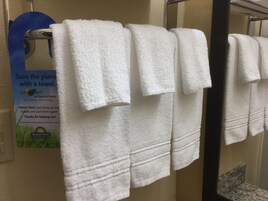 A row of white towels hanging on a rack in a bathroom.