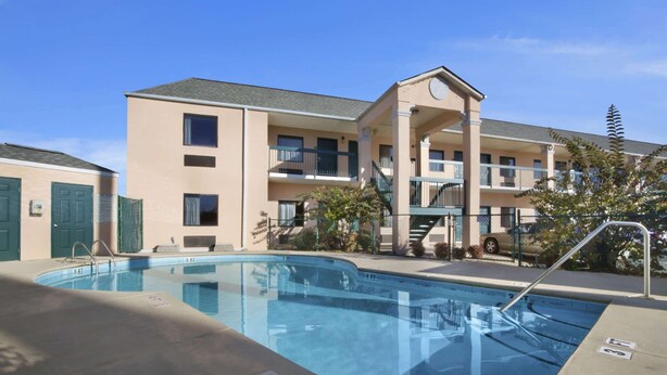 A swimming pool adjacent to a multi-story building with balconies and a covered walkway. - Days Inn By Wyndham Lexington/Columbia (Lexington)