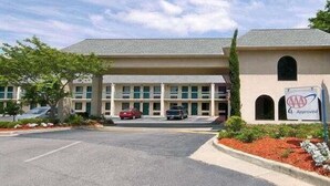 A multi-story building with a parking lot, a sign indicating approval, and a clear sky. - Days Inn By Wyndham Lexington/Columbia (Lexington)