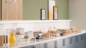 A modern kitchen with a white countertop, a coffee machine, a toaster, and a bread display. - Spark by Hilton Houston Bush Intercontinental Airport (Houston)