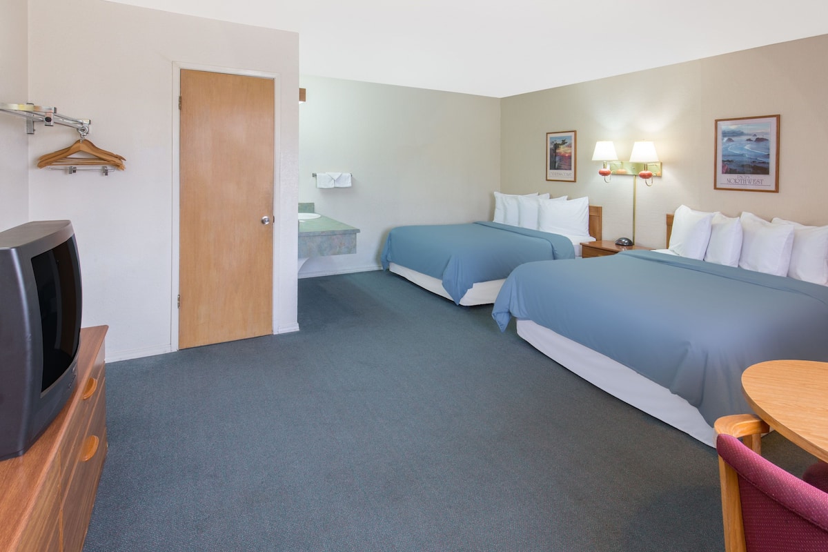 A hotel room with two beds, a TV, a desk, and a chair.