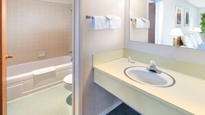 Un baño moderno con una bañera, un lavabo y un espejo grande.