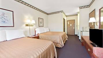 Une chambre d’hôtel avec deux lits, une télévision, une commode et une porte donnant sur une autre pièce.