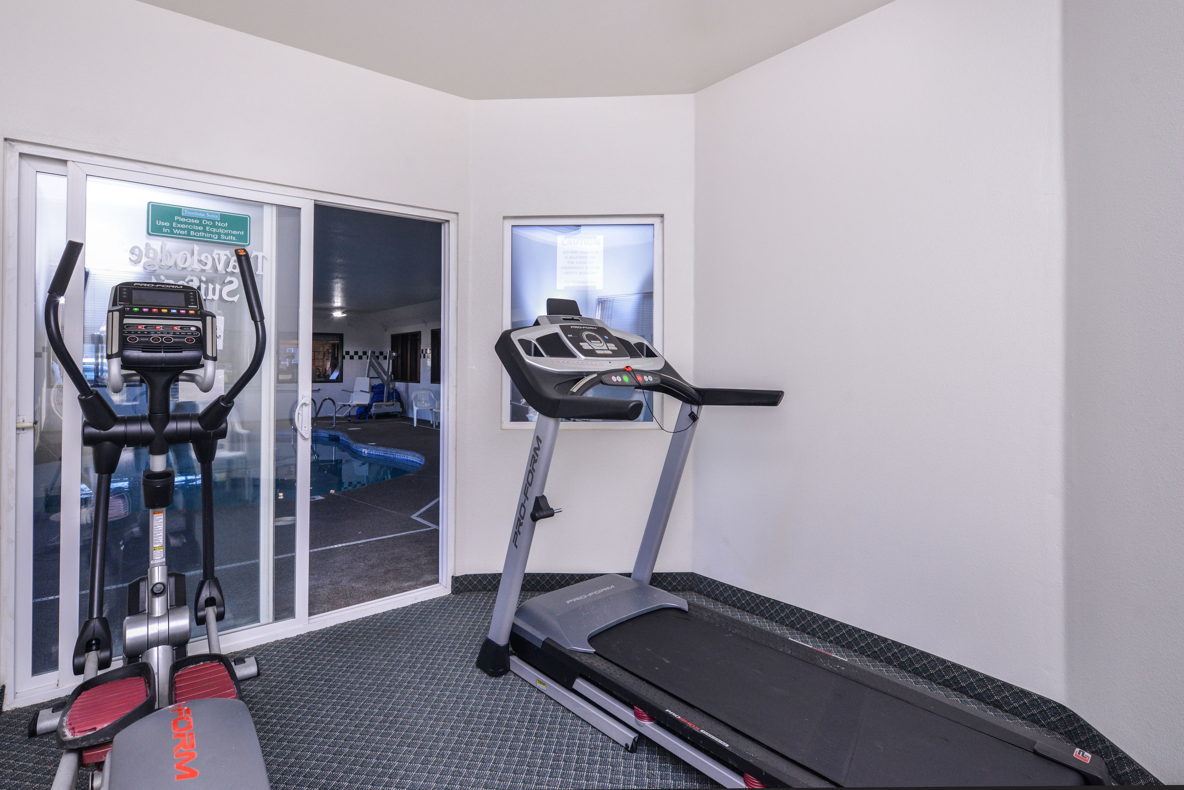 A gym with a stationary bike, elliptical, and treadmill.