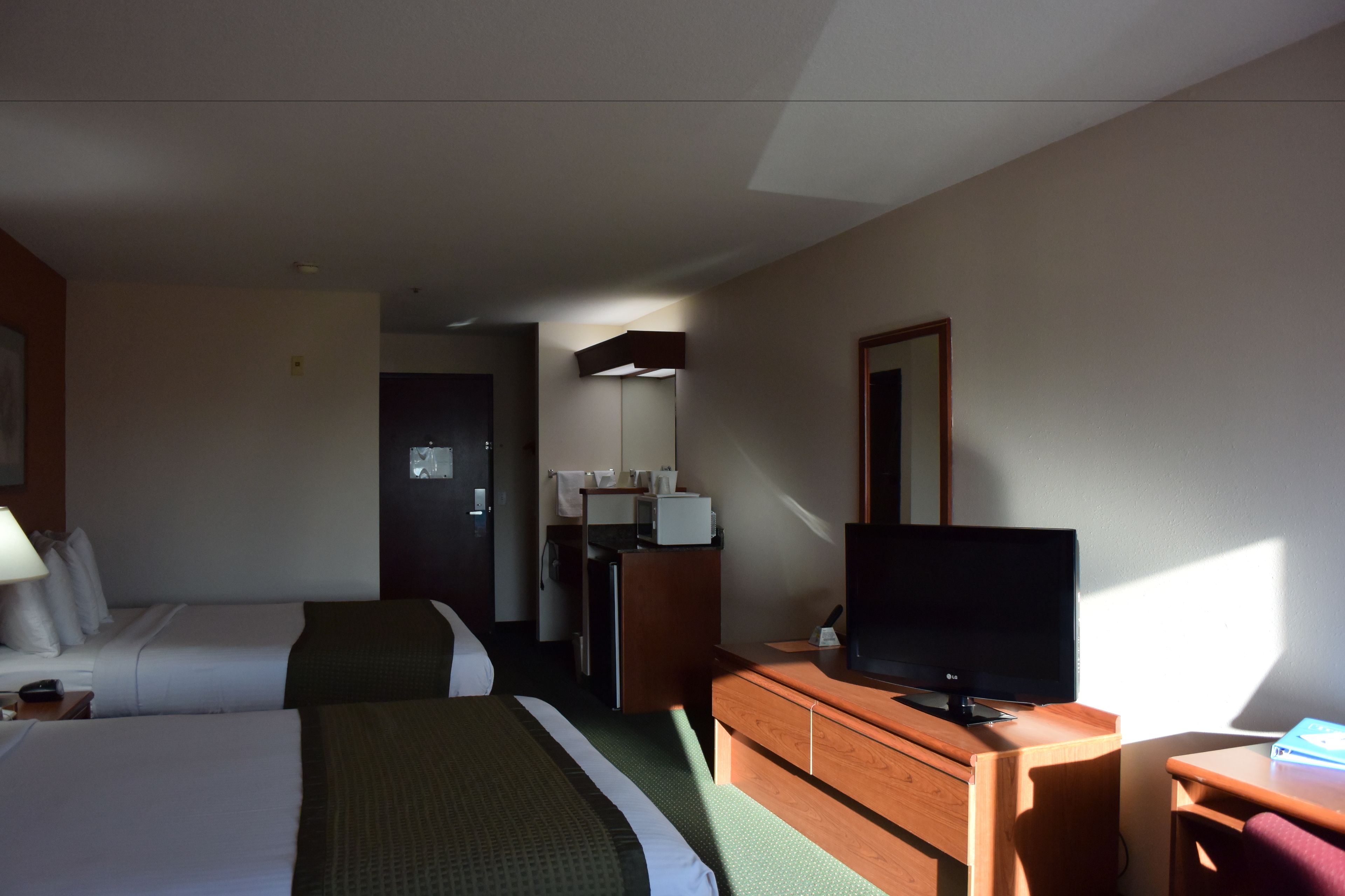 Une chambre d’hôtel avec deux lits, une télévision, un bureau et une kitchenette.