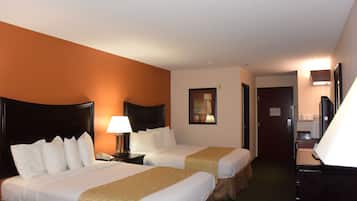 Una habitación de hotel con dos camas, un escritorio, una silla, una lámpara y una puerta.
