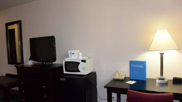 Hotelkamer met een bureau, een magnetron, een televisie, een lamp, een telefoon en een blauw bordje met de tekst