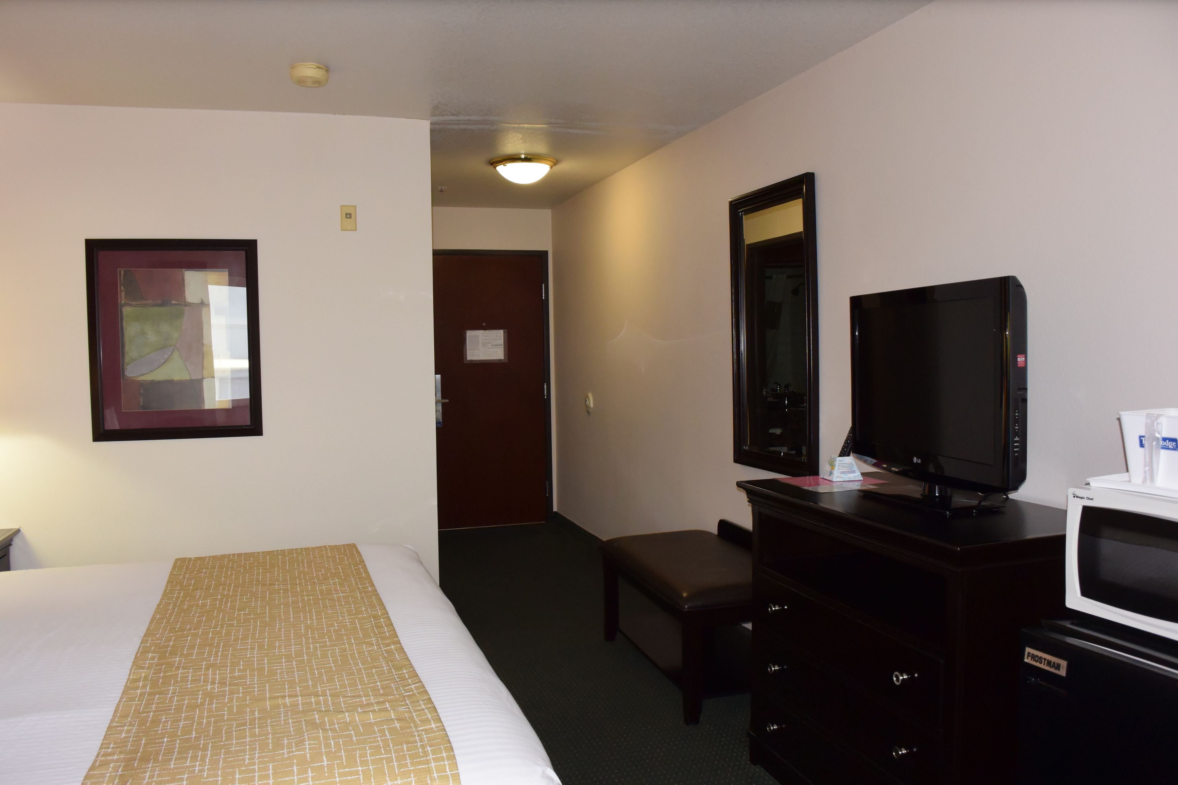 A hotel room with a bed, a television, a dresser, and a microwave.