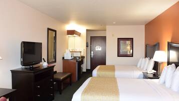 A hotel room with a bed, a desk with a television, a desk lamp, a chair, and a door.