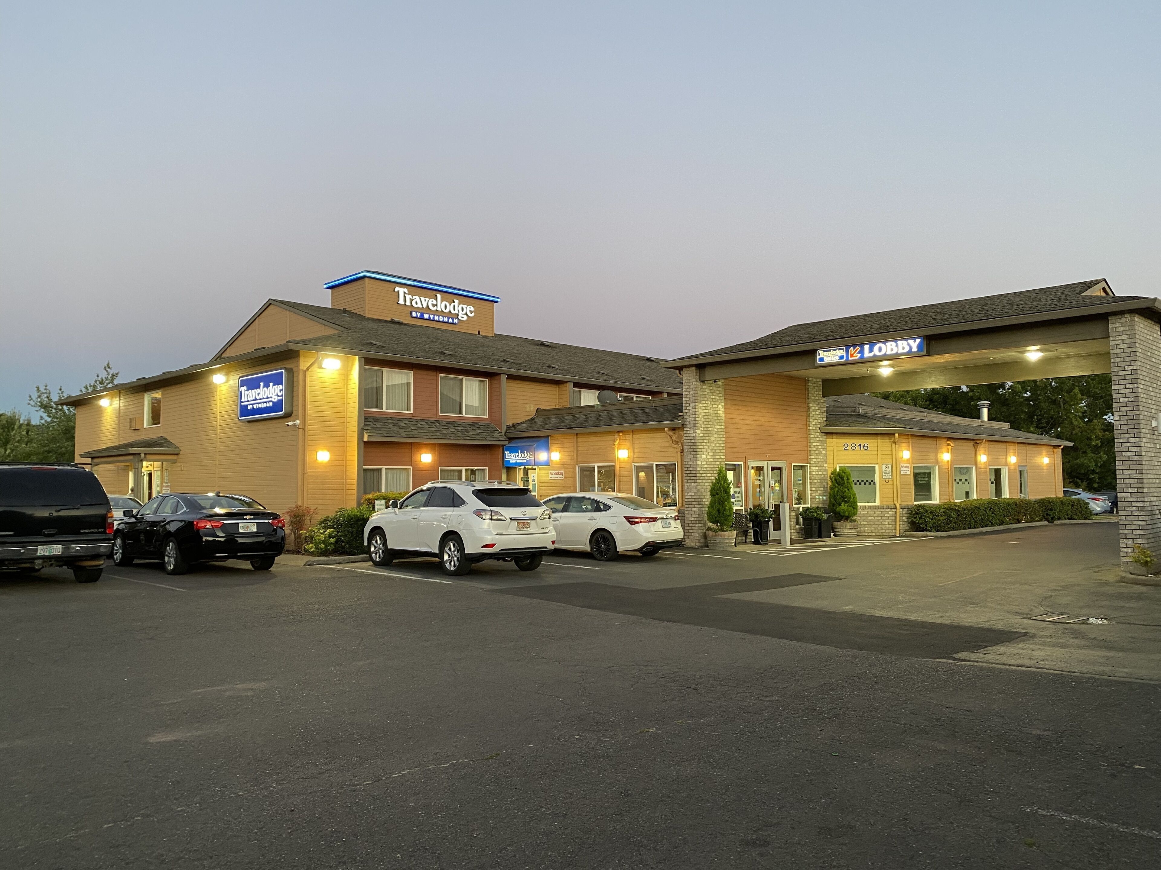 A Travelodge hotel with a parking lot and several cars parked in front.