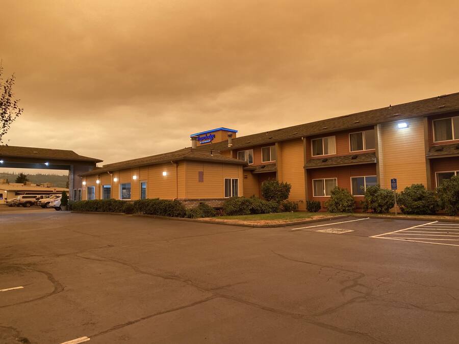A motel with a parking lot and a building with a sign reading "Travelodge."