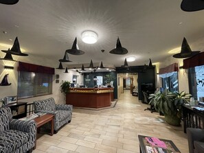 Un vestíbulo de hotel con una recepción, sofás con diseño, una mesa de centro y una planta grande en maceta.