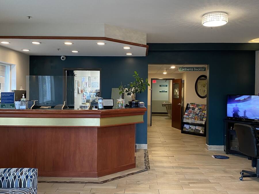 A reception area with a wooden counter, a computer, a coffee machine, and a television.