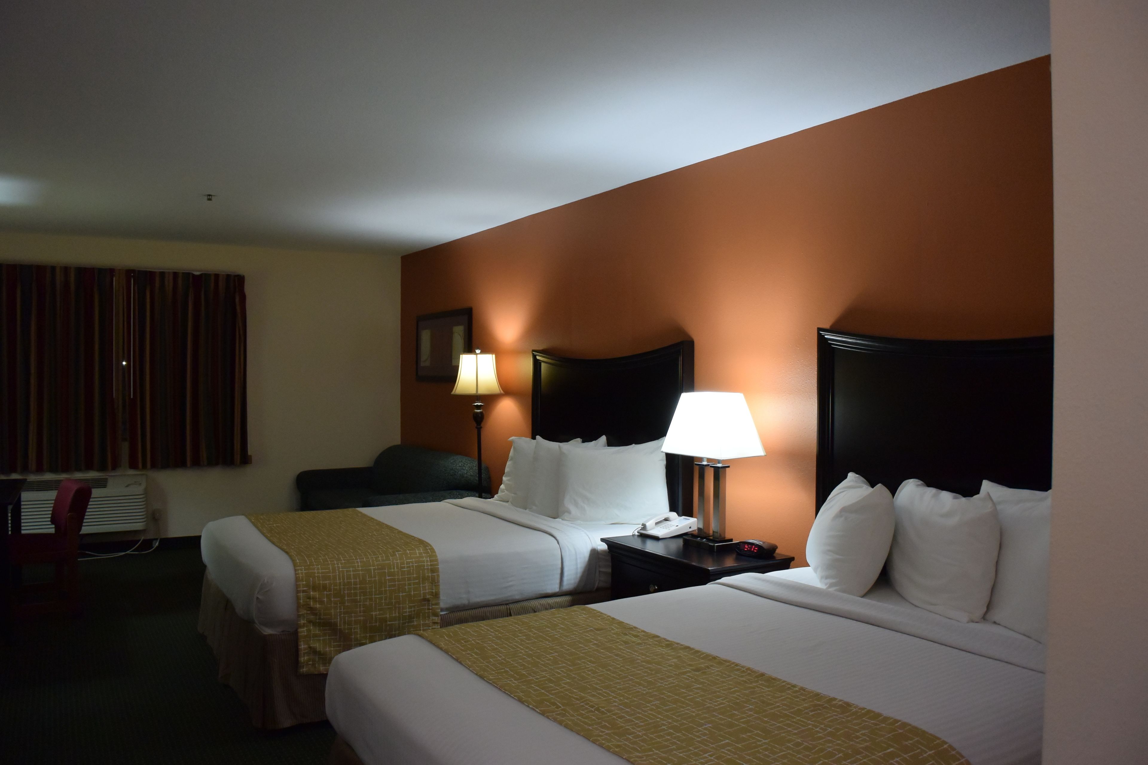 Habitación de hotel con dos camas, un escritorio y una silla.