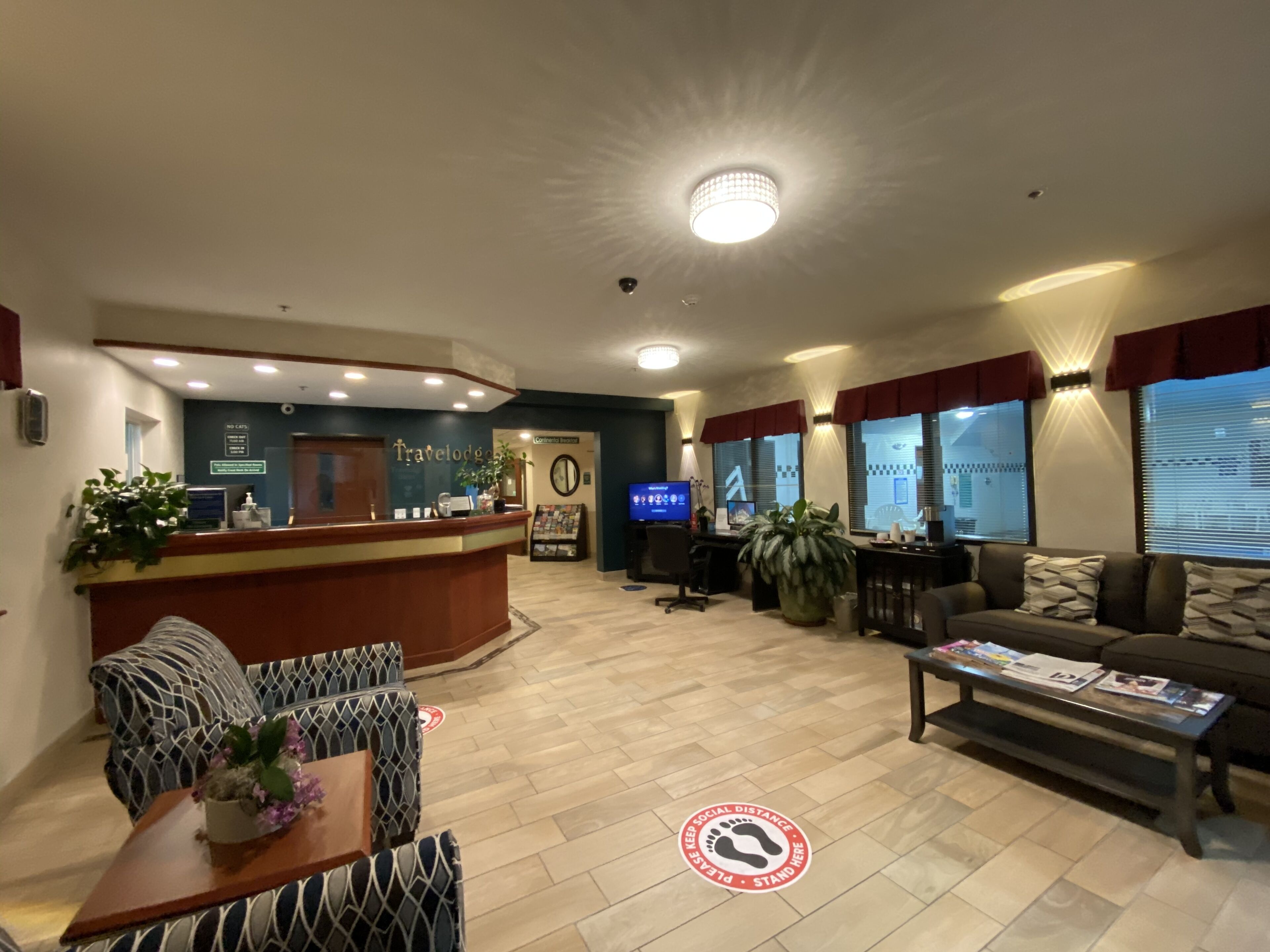 Un hall de hotel con mostrador de recepción, zona de estar y televisor.