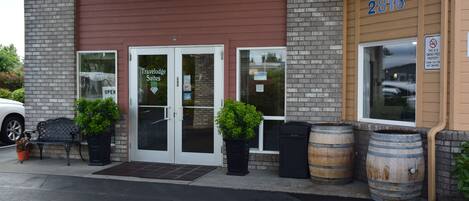 A building with a sign reading "Travelodge Suites" and the number 2816. There are potted plants and wooden barrels outside.