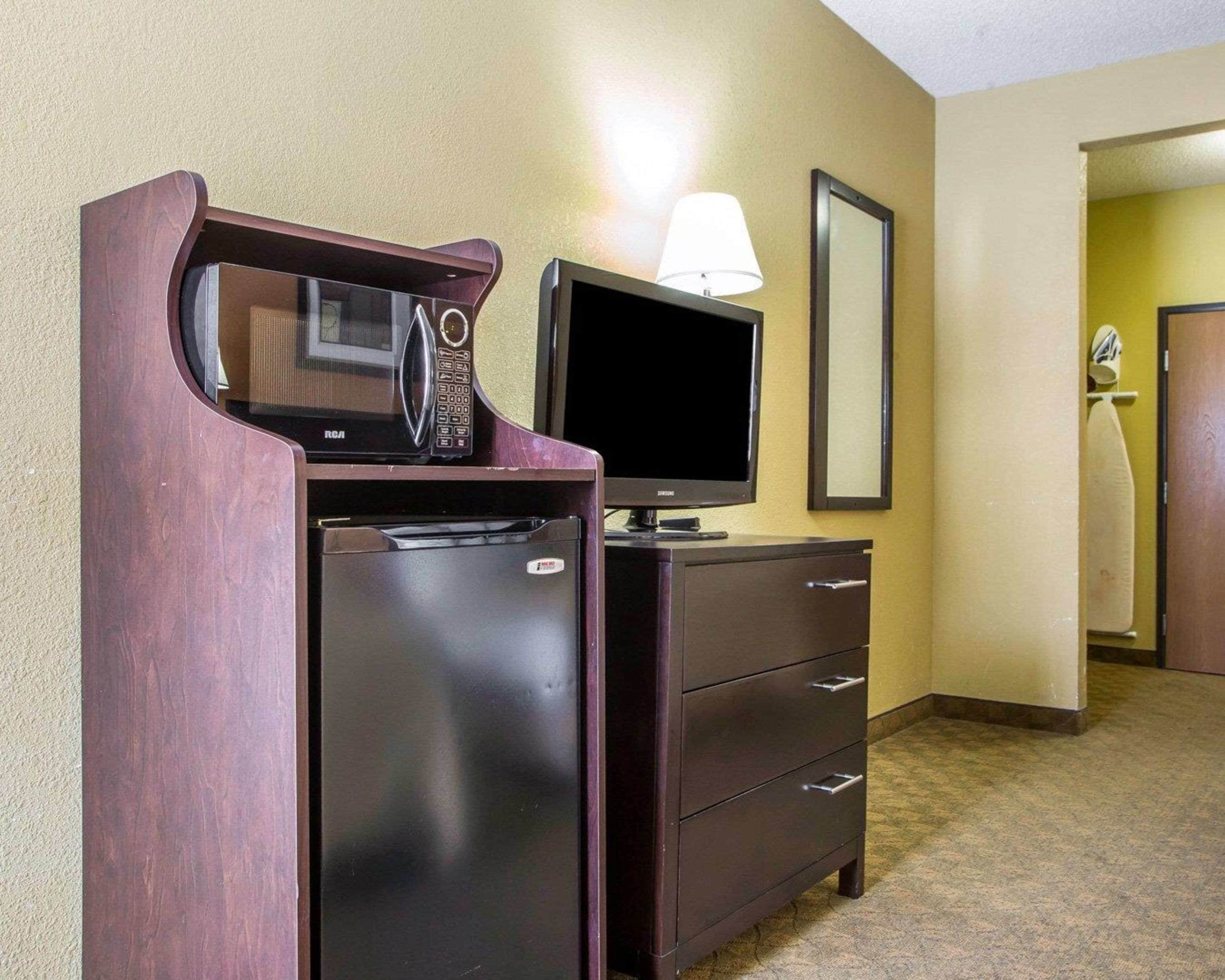 A hotel room with a minibar, a television, and a lamp.