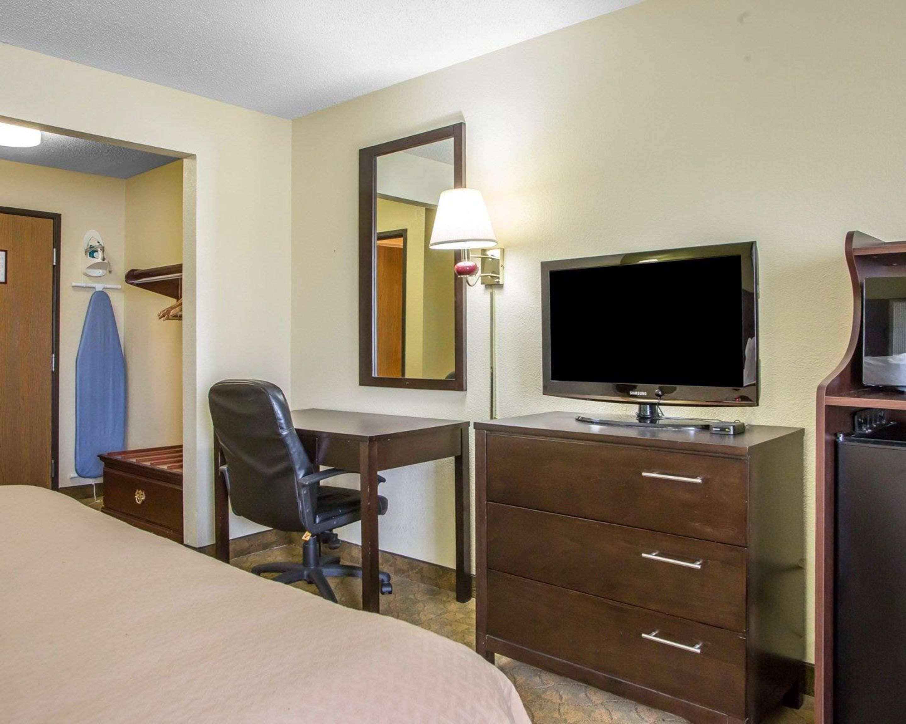 Une chambre d’hôtel comprenant un lit, un bureau avec une chaise, une télévision, une commode et un miroir.
