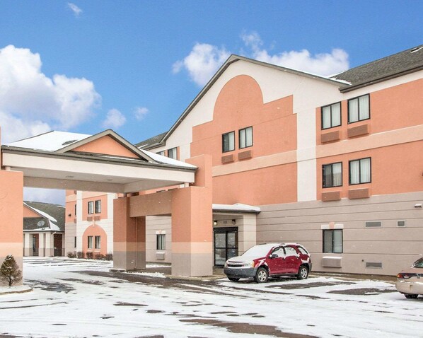 A multi-story hotel with a flat roof and a covered parking area.