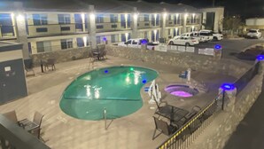 A hotel with a swimming pool, outdoor seating, and a parking area. - Days Inn by Wyndham El Paso West (El Paso)
