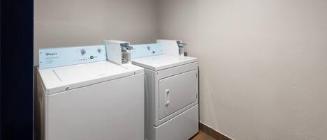 A laundry room with two Whirlpool washers and a stacked dryer.