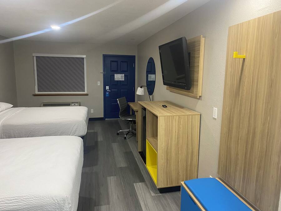 A hotel room with two beds, a desk with a computer, a TV, and a wardrobe.