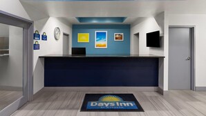 A reception desk with a blue wall, a clock, and a 'Days Inn' doormat. - Days Inn by Wyndham El Paso West (El Paso)