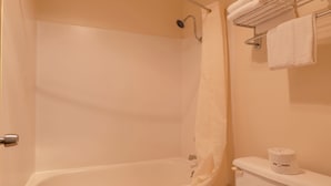 Une salle de bain équipée d’une baignoire, d’un rideau de douche, d’un porte-serviettes avec des serviettes et de toilettes avec du papier toilette.