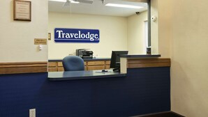 A reception desk with a 'Travelodge' sign, a computer, and a telephone. - Travelodge by Wyndham Grand Island (Grand Island)