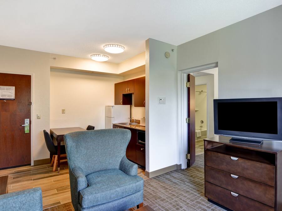 A modern living room with a flat-screen TV, a blue armchair, and a wooden dresser.