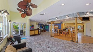 A spacious lobby with a high ceiling, a large fan, and a reception desk.