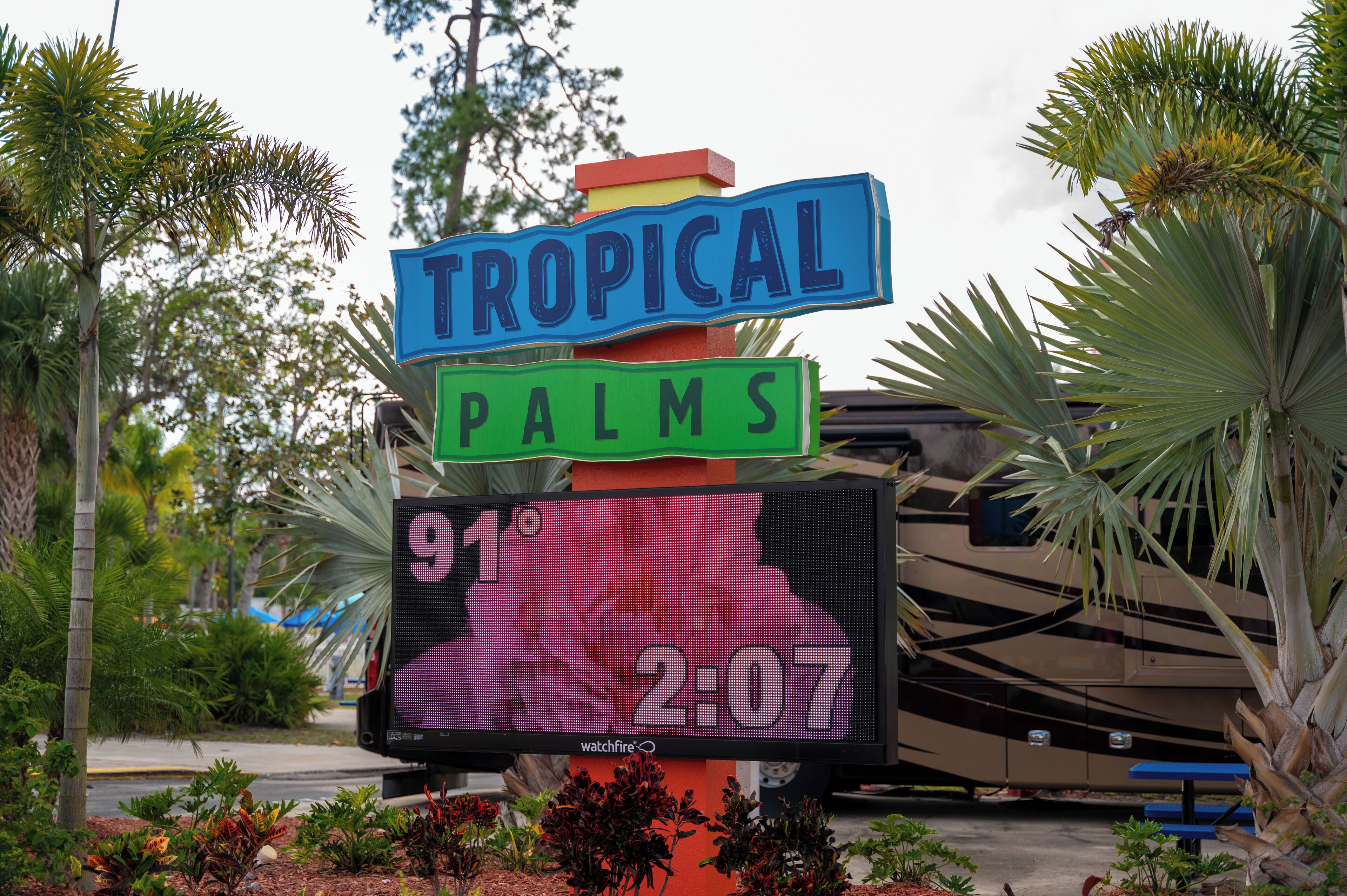 Un letrero con 'TROPICAL PALMS' y una pantalla digital que muestra la temperatura y la hora.