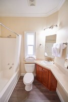 Une salle de bain avec une baignoire, des toilettes, un lavabo et une fenêtre.