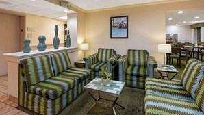 Un hall d'hôtel avec des canapés à motifs, une petite table sur laquelle est posé un vase, et un comptoir d'accueil.