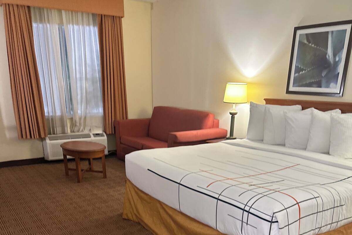 Ein Hotelzimmer mit einem großen Bett, einem roten Sofa, einem kleinen Tisch und einer Lampe.