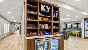 A snack display with various packaged foods and a refrigerated section with beverages. - Hampton Inn Lexington/Georgetown (Georgetown)