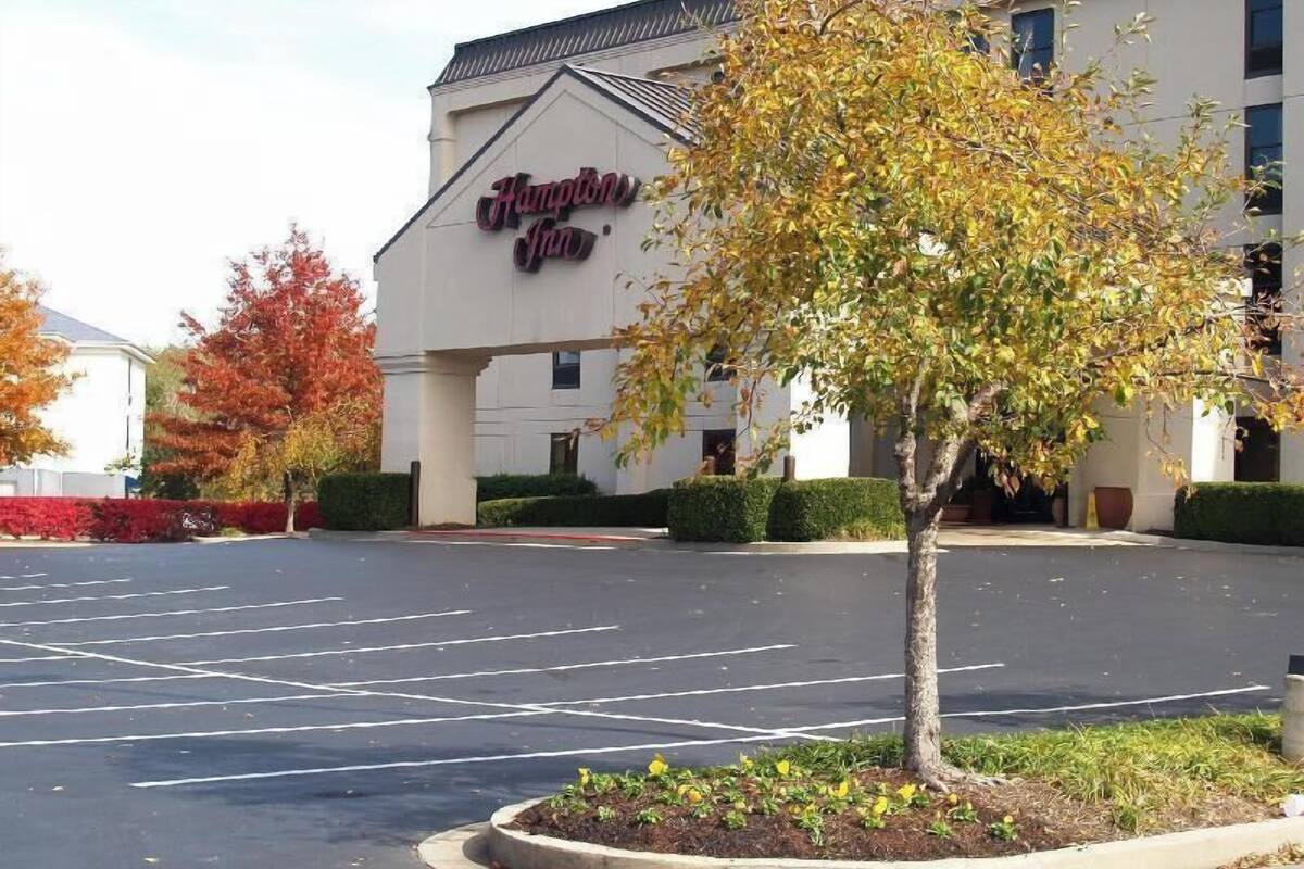 A Hampton Inn with a parking lot and a tree in the foreground.