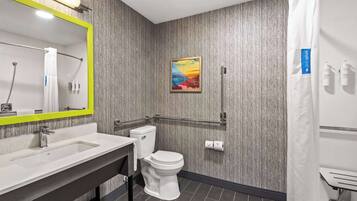 A modern bathroom with a large mirror, a sink, a toilet, and a shower curtain.