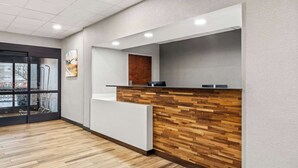 A reception area with a wooden reception desk, a white counter, and a window with a view of outdoor equipment. - Hampton Inn Lexington/Georgetown (Georgetown)