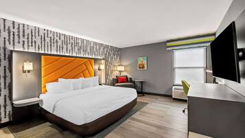 A modern hotel room with a large bed, a TV, a desk, and a window.