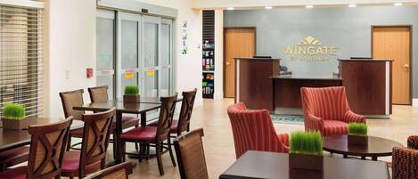 Un vestíbulo de hotel con mostrador de recepción, zona de estar y una escalera.