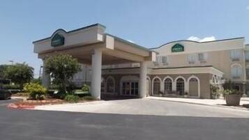 A hotel with a central entrance, a covered parking area, and a building with arched windows.