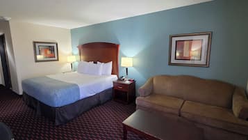 A hotel room with a bed, a sofa, a desk, and two lamps.